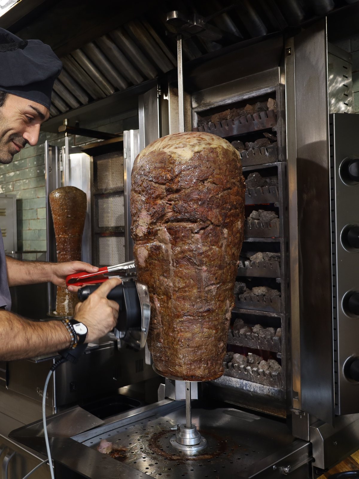 Steakfleisch aus der Hochrippe wird mit dem Elektromesser frisch vom Spieß geschnitten