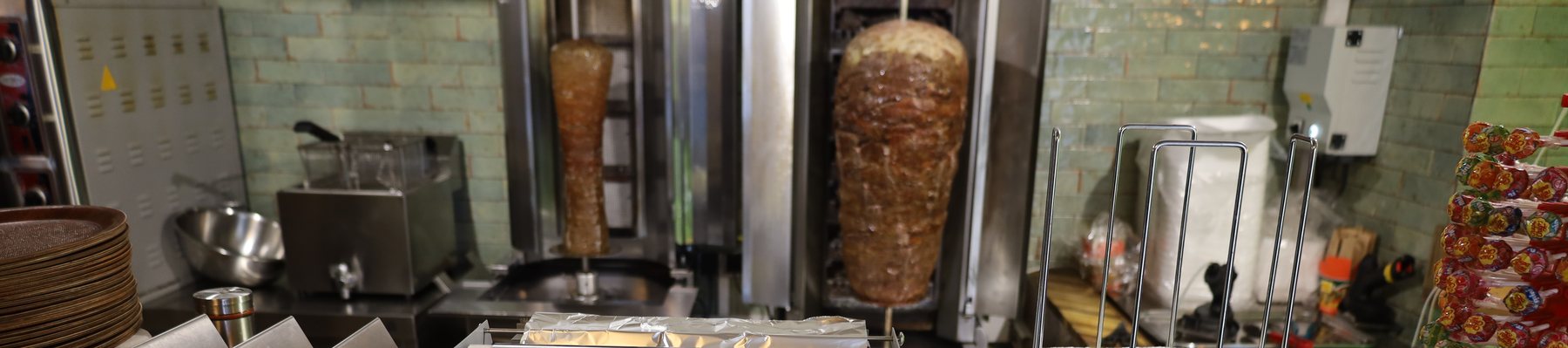 Zwei fertige Dönerspieße vor der grün gefliesten Wand